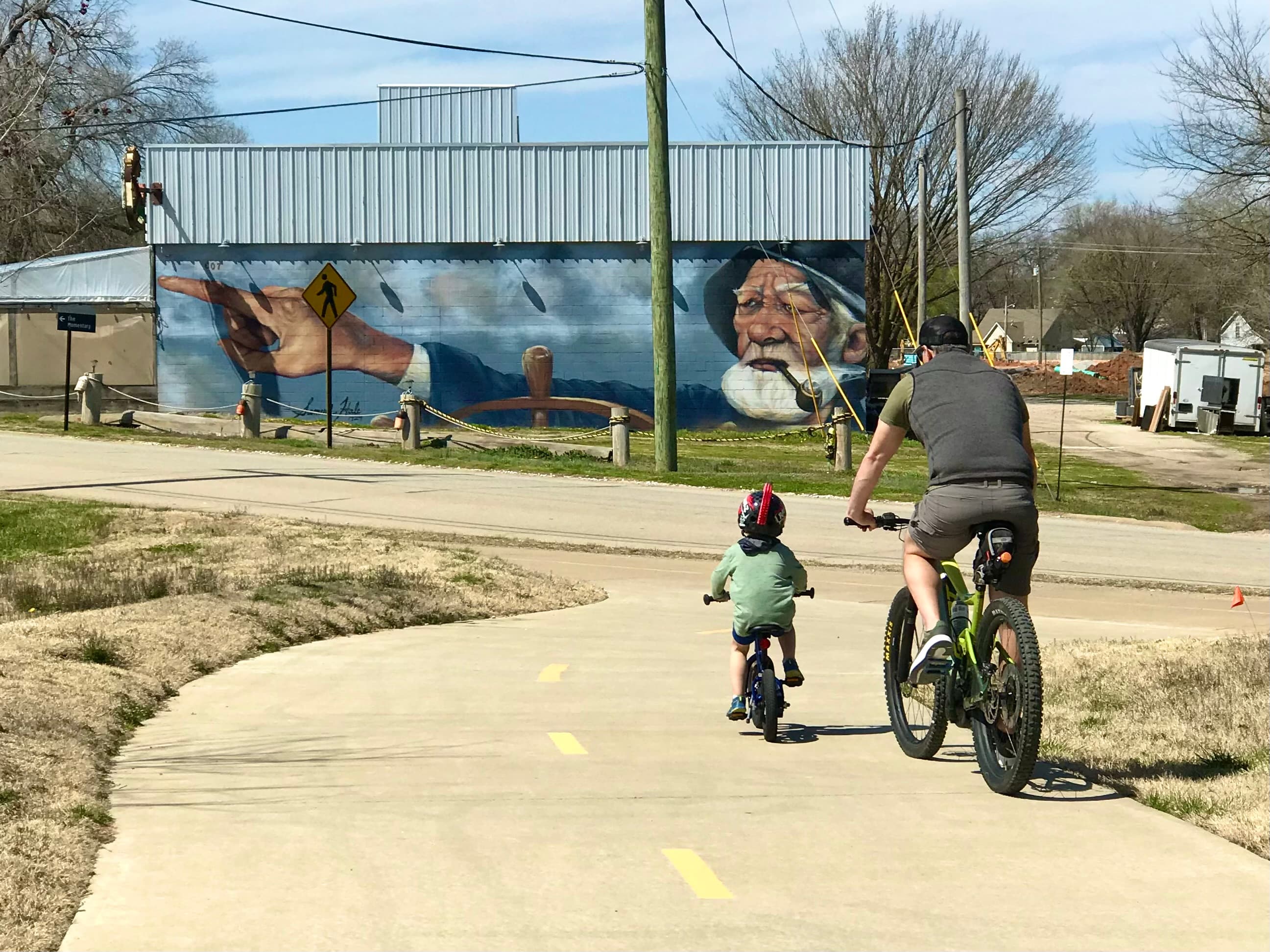 Dad and child biking near public art
