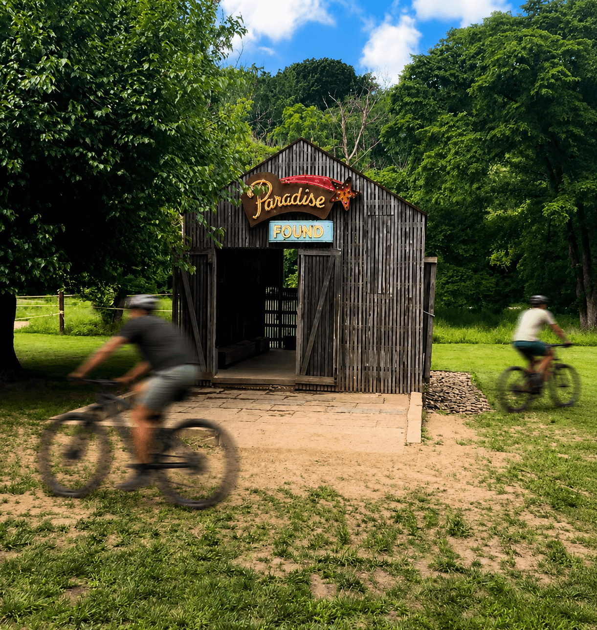 Paradise Found barn at Coler Preserve with cyclists moving through the landscape